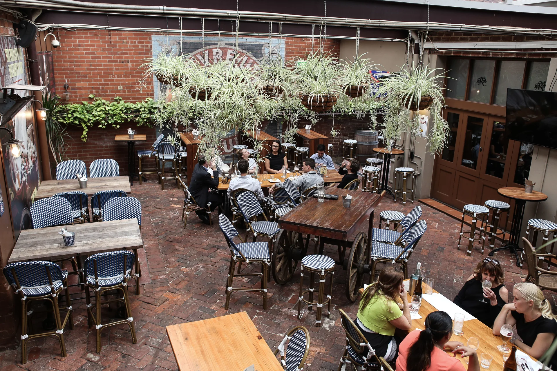 Terraza urbana con mesas, vegetación y clientes